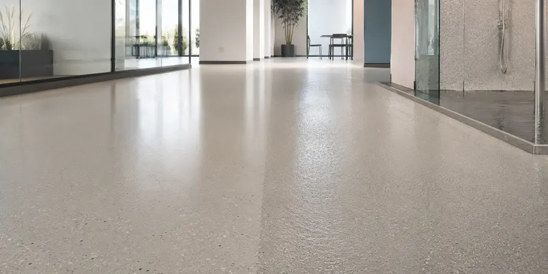 Continuous fine-aggregate resin floor finish in a bright interior passage.